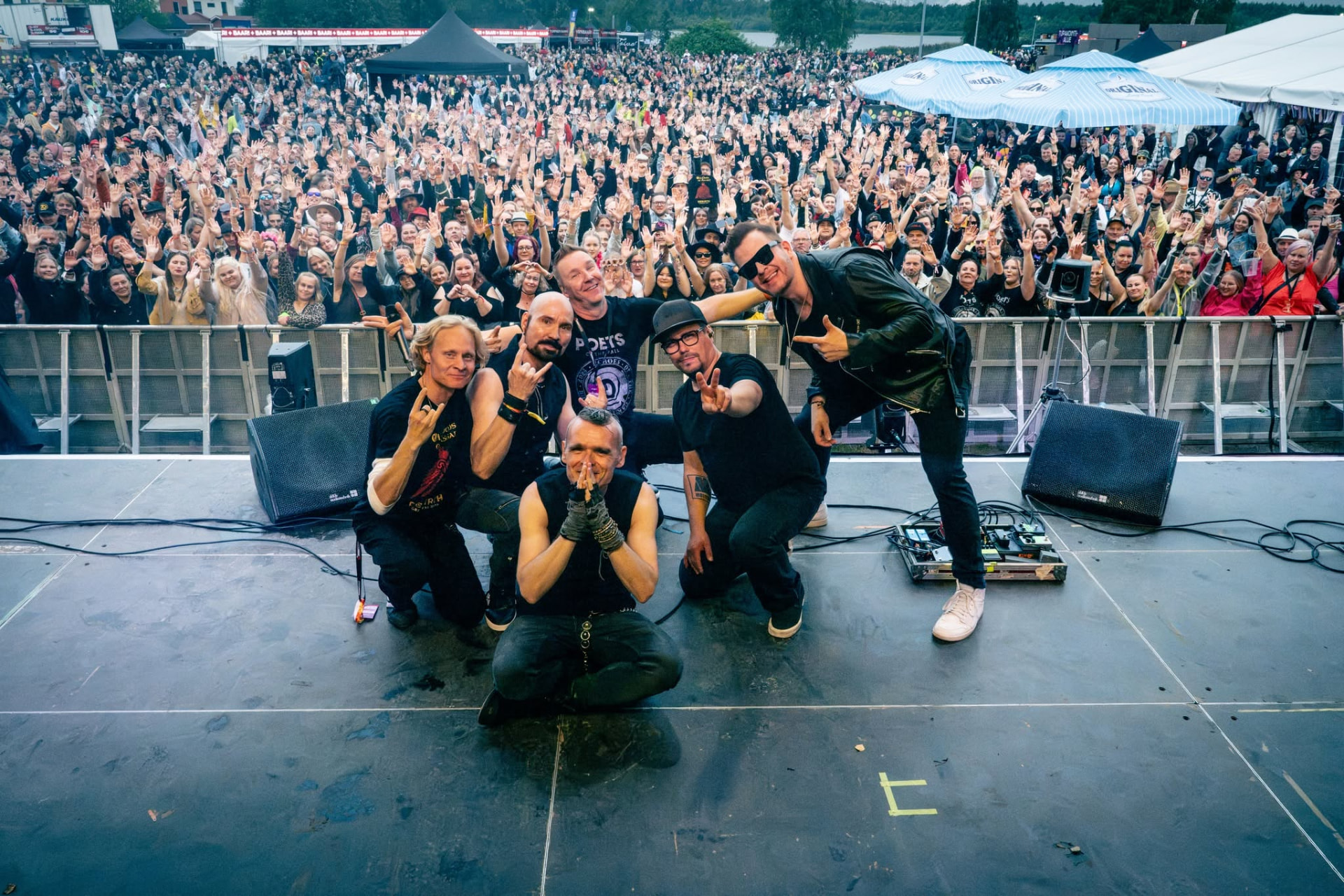 Poets of the Fall posing on stage with the audience at a summer concert
