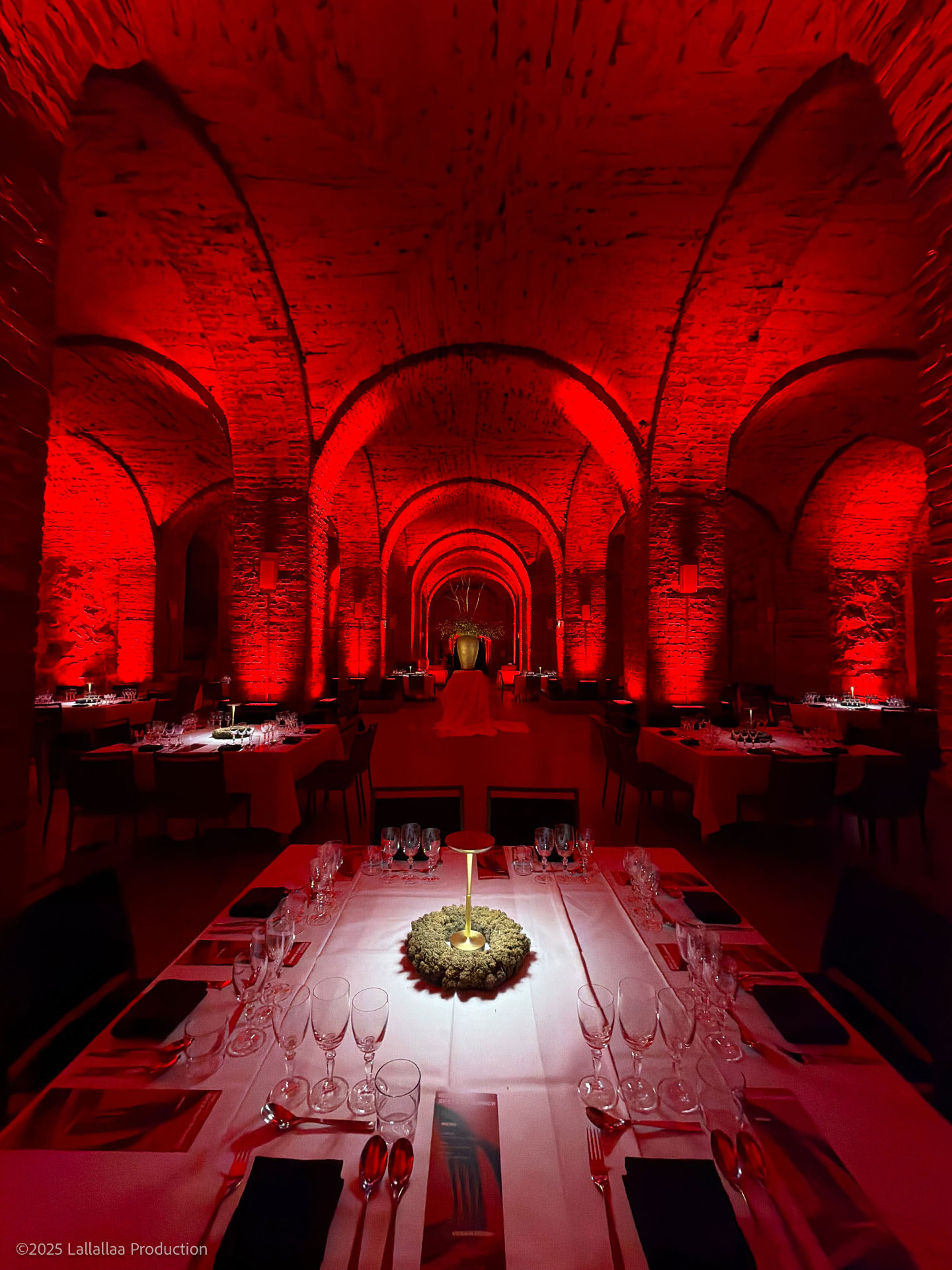 Slush Speaker Dinner in the Crypt: long set tables under red-lit stone vaults